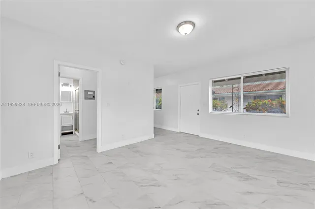 an empty room with windows and refrigerator