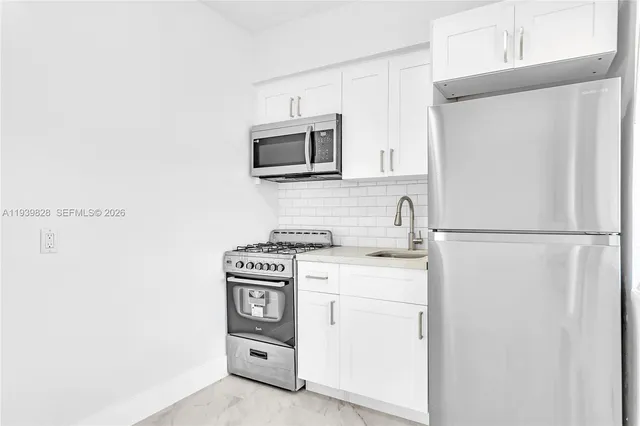 a kitchen with white cabinets and stainless steel appliances