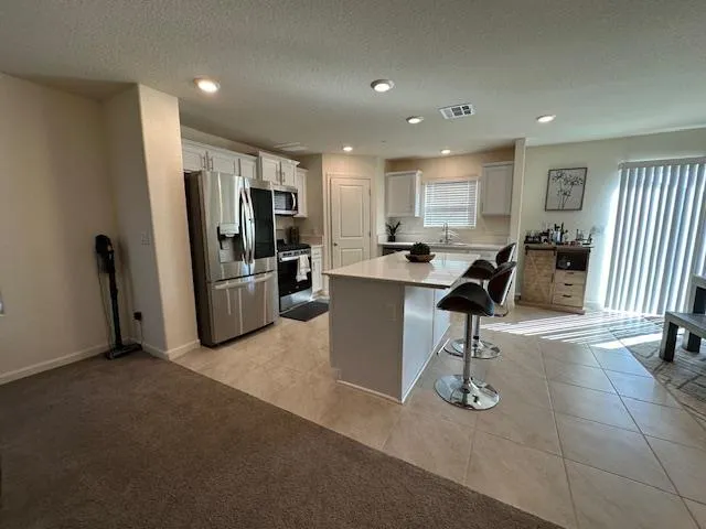a view of a kitchen with refrigerator and chairs