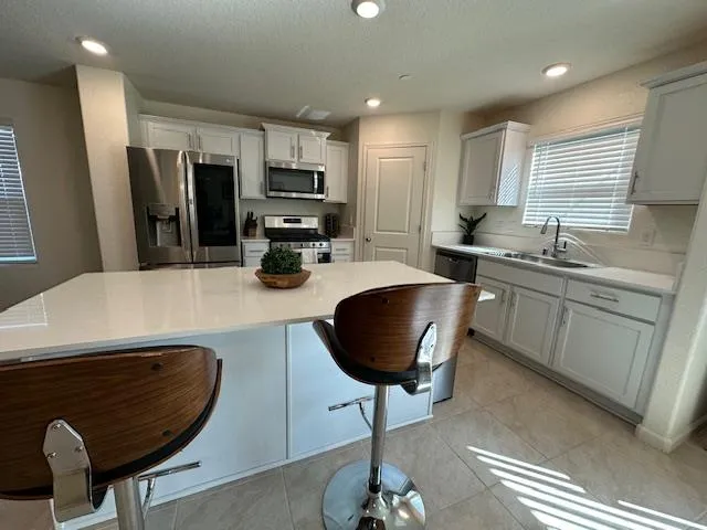 a kitchen with stainless steel appliances kitchen island granite countertop a sink a stove a refrigerator cabinets and chairs