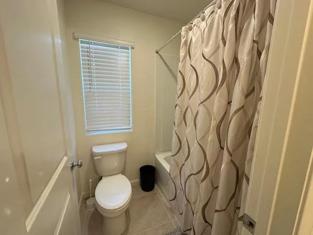 a bathroom with a toilet and a shower curtain