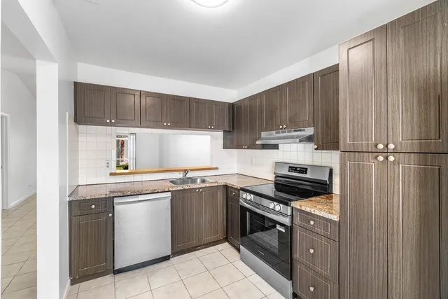a kitchen with stainless steel appliances granite countertop a stove a sink and a refrigerator