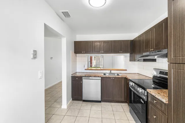 a kitchen with stainless steel appliances granite countertop a stove top oven sink and cabinets