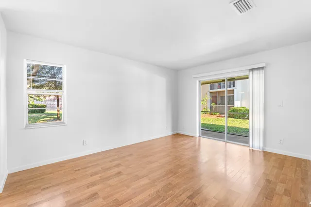 an empty room with wooden floor and windows