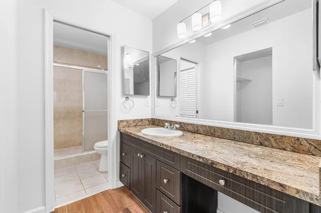 a bathroom with a granite countertop sink a toilet and a shower