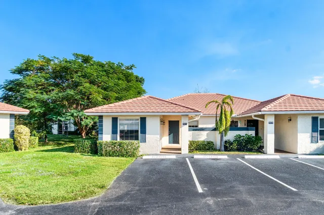 a view of a white house with a yard and potted plants