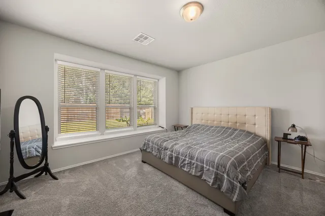 a bedroom with a bed a table and windows