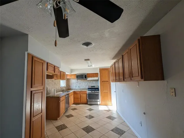 a kitchen with stainless steel appliances a refrigerator and a stove top oven