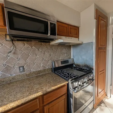 a kitchen with granite countertop cabinets stove top oven and microwave