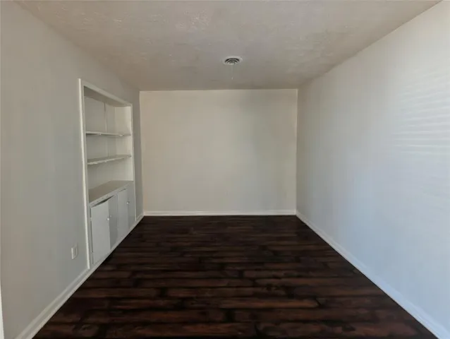 a view of an empty room with wooden floor and closet