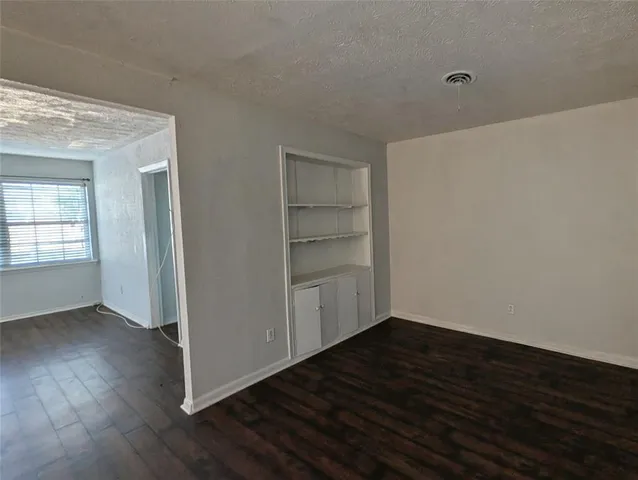 an empty room with wooden floor & closet area