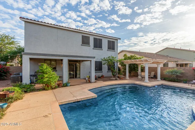 a view of swimming pool with a lawn chairs and palm tree