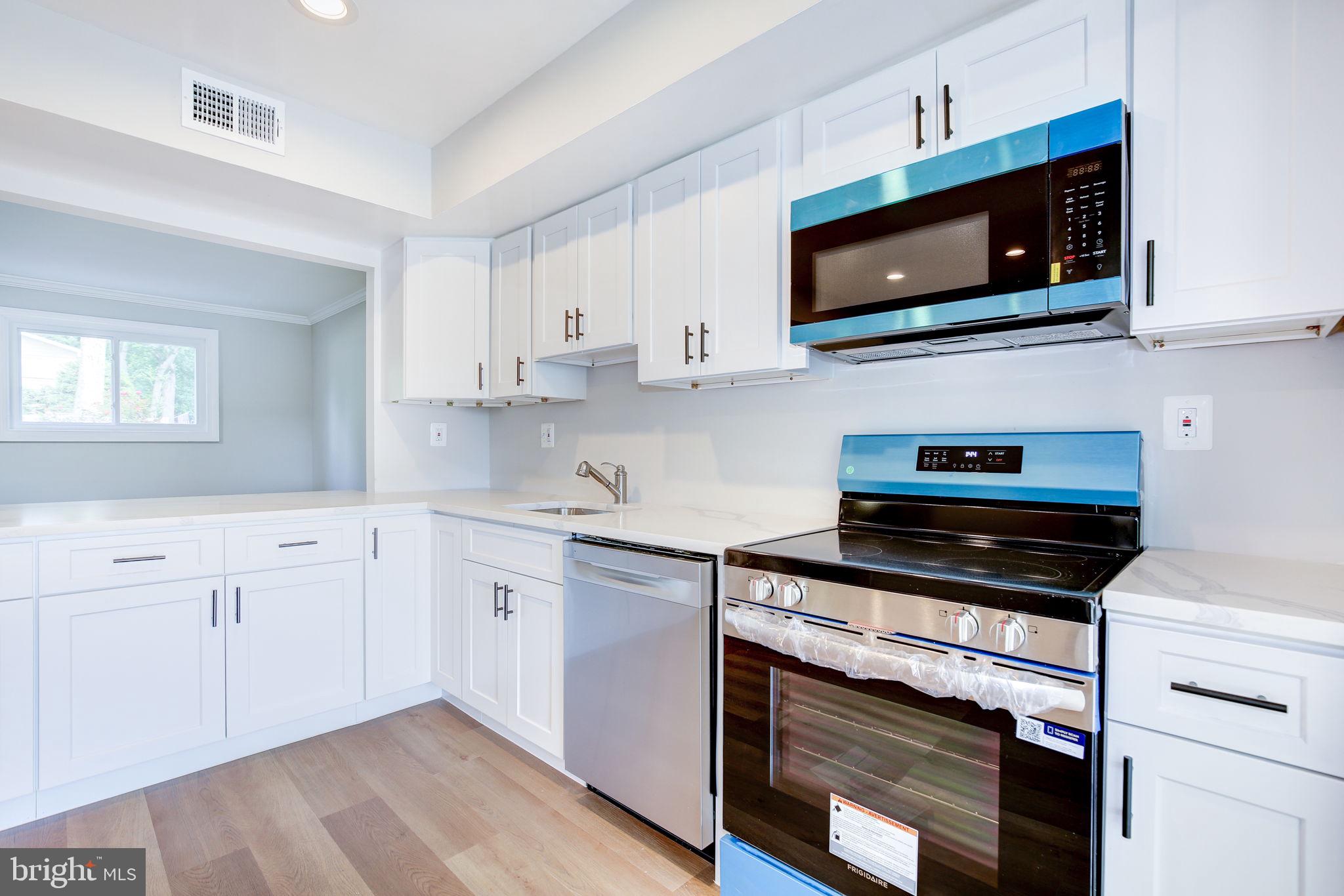 11830 Charles Road Silver Spring, MD 20906 - Photo 31 of 54 a kitchen with cabinets stainless steel appliances and wooden floor