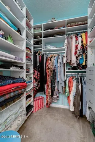 a view of walk in closet with clothes and shoes