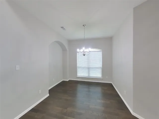 an empty room with wooden floor fan and window