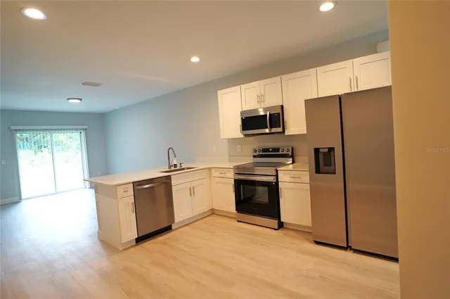 a kitchen with granite countertop a refrigerator and a stove top oven