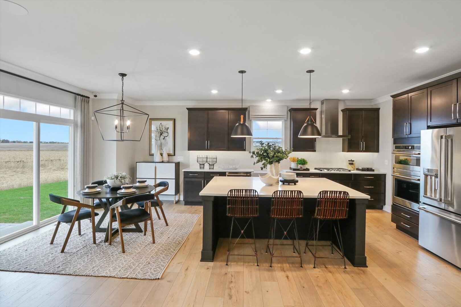 13044 South Boulder Lane Plainfield, IL 60585 - Photo 8 of 36 a kitchen with stainless steel appliances kitchen island granite countertop a table chairs sink and cabinets