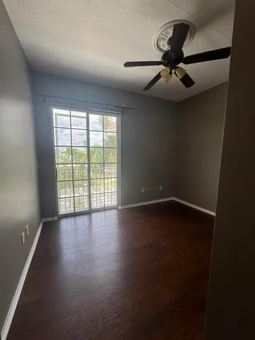 an empty room with wooden floor fan and windows