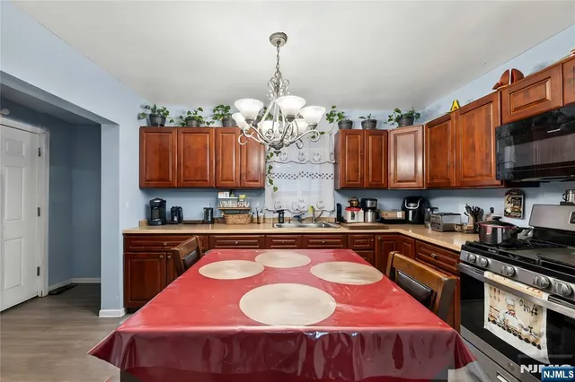 a kitchen with stainless steel appliances granite countertop a stove a sink dishwasher and microwave with wooden floor