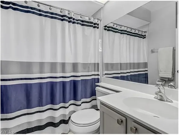 a bathroom with a sink a toilet a mirror and shower curtain