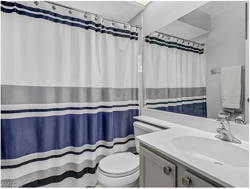 13060 Amberley Court, Unit 807 Bonita Springs, FL 34135 - Photo 16 of 33 a bathroom with a sink a toilet a mirror and shower curtain