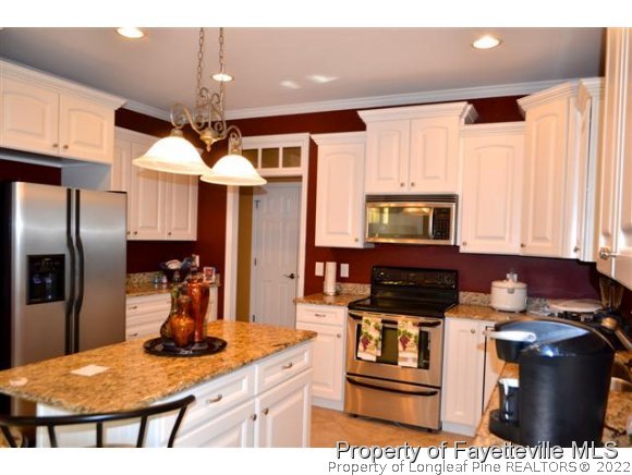 95 Falling Water Road Spring Lake, NC 28390 - Photo 11 of 20 a kitchen with stainless steel appliances kitchen island granite countertop a refrigerator a stove and a sink with wooden floor