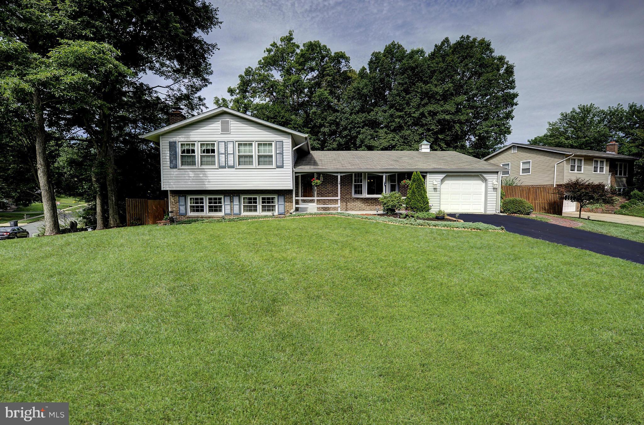 8609 Woodview Drive Springfield, VA 22153 - Photo 1 of 28 a front view of a house with a garden and trees