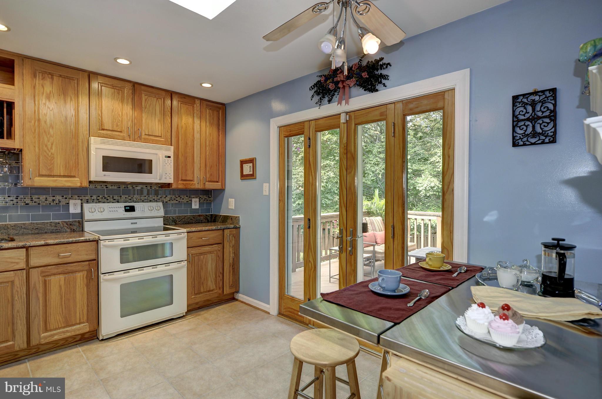 8609 Woodview Drive Springfield, VA 22153 - Photo 14 of 28 a kitchen with stainless steel appliances kitchen island granite countertop a table chairs stove and cabinets