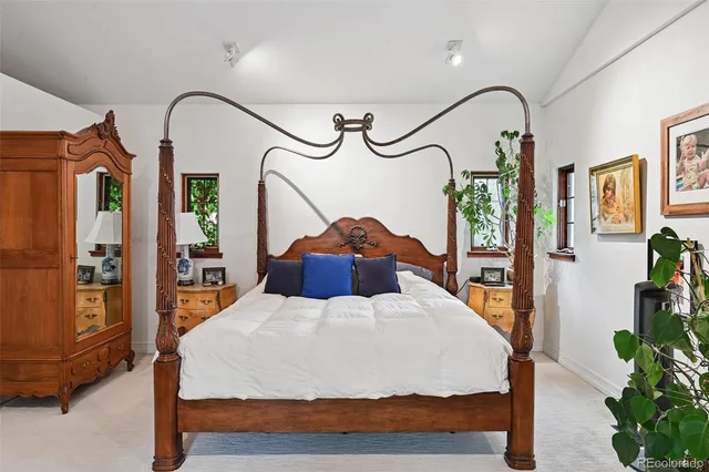 a bedroom with a bed a mirror on dresser and a flat screen tv
