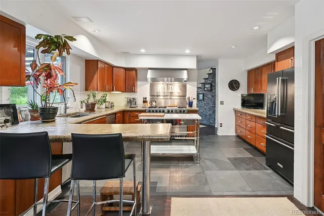 a kitchen with a stove a sink dishwasher a dining table and chairs with wooden floor