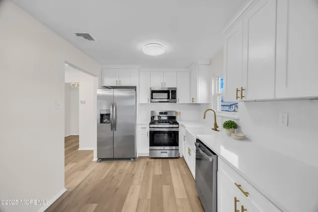a kitchen with white cabinets and stainless steel appliances