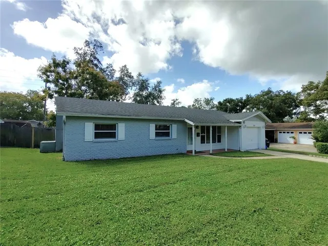 a house that is sitting in the grass with large trees