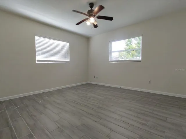 a view of empty room with wooden floor and fan