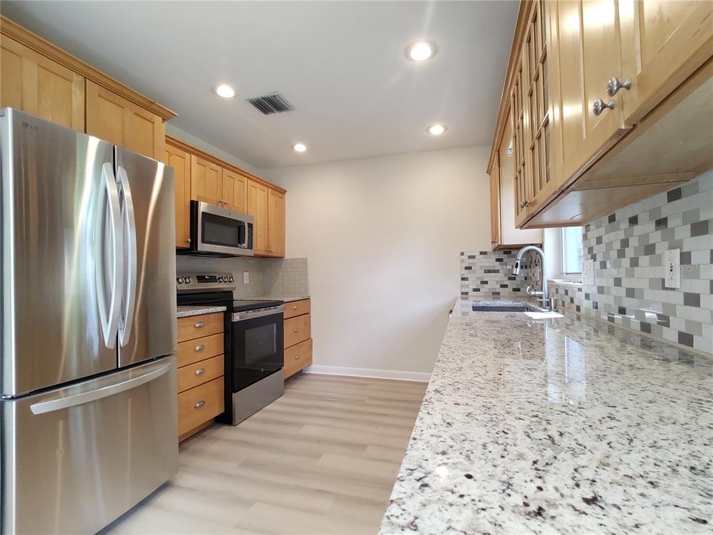 516 Ellsworth Street Altamonte Springs, FL 32701 - Photo 3 of 30 a kitchen with stainless steel appliances granite countertop a refrigerator a stove and a sink