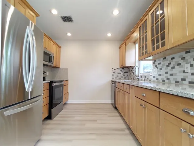 a kitchen with stainless steel appliances granite countertop a refrigerator a stove and a sink