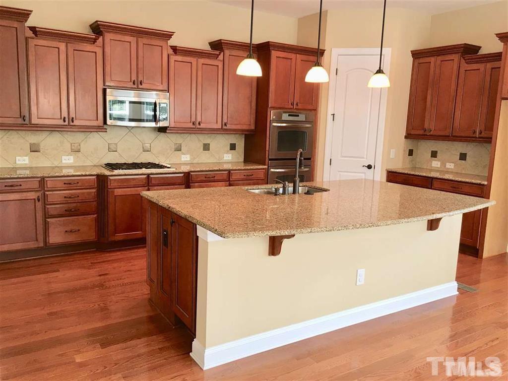 8505 Stonechase Drive Raleigh, NC 27613 - Photo 5 of 24 a kitchen with kitchen island granite countertop wooden cabinets a stove a sink and dishwasher with wooden floor