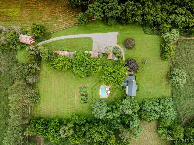 an aerial view of a residential houses with outdoor space and trees all around