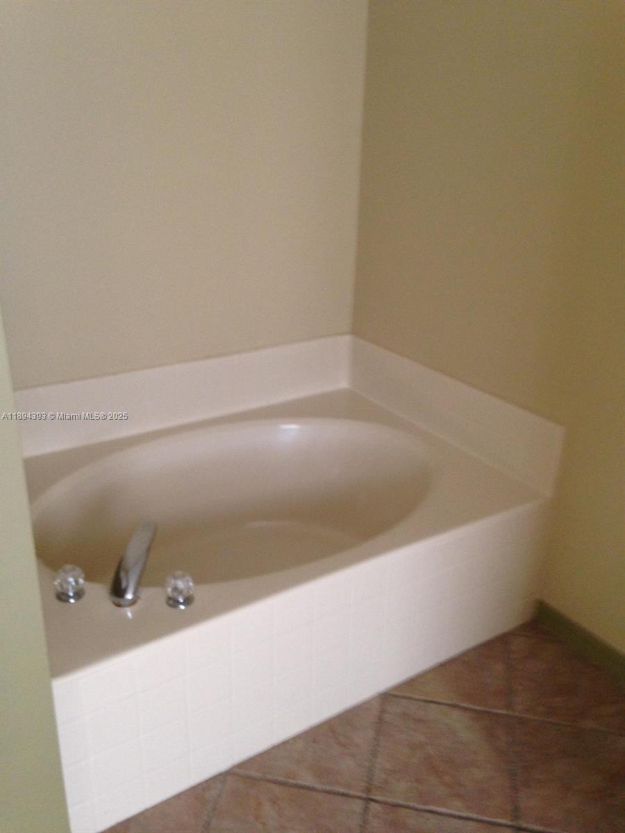 4634 Southwest Eagle Street Port St. Lucie, FL 34953 - Photo 3 of 16 a bath tub sitting next to a white sink and vanity