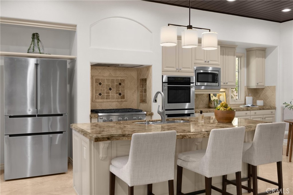 34 Tall Hedge Irvine, CA 92603 - Photo 32 of 75 a kitchen with stainless steel appliances granite countertop a refrigerator a stove a microwave oven a sink with island and chairs