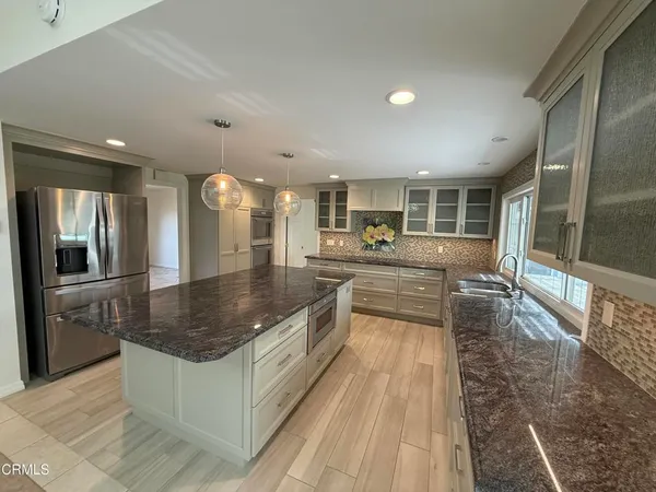 a large kitchen with kitchen island a large counter top and stainless steel appliances