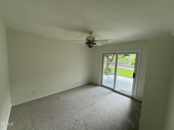 an empty room with windows and fan