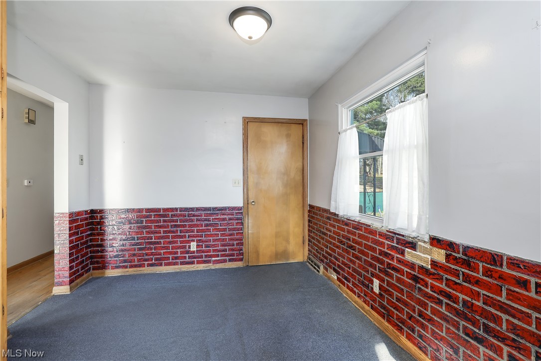 3373 Cormany Road Akron, OH 44319 - Photo 8 of 29 Empty room with dark wood-type flooring and brick wall