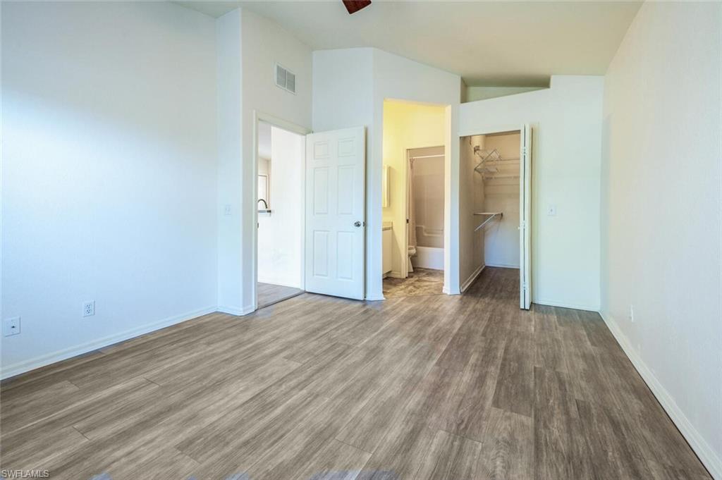 135 Blue Ridge Drive, Unit 35 Naples, FL 34112 - Photo 9 of 23 Unfurnished bedroom with baseboards, visible vents, wood finished floors, and lofted ceiling