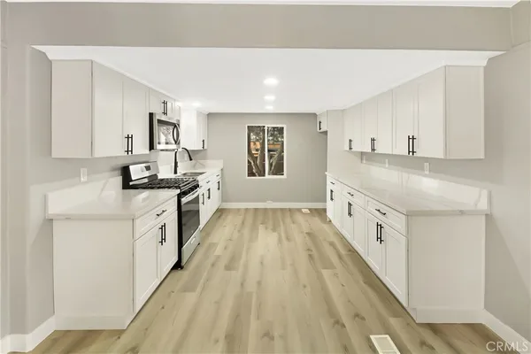 a kitchen with granite countertop a sink stove top oven and cabinets