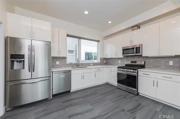a kitchen with a refrigerator stove and wooden floor
