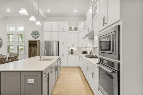 a kitchen with stainless steel appliances kitchen island a table chairs sink and cabinets