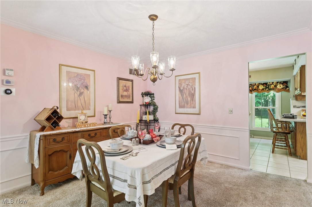 5568 Forest Glen Road Madison, OH 44057 - Photo 9 of 50 Dining room featuring a chandelier, light carpet, ornamental molding, and wainscoting