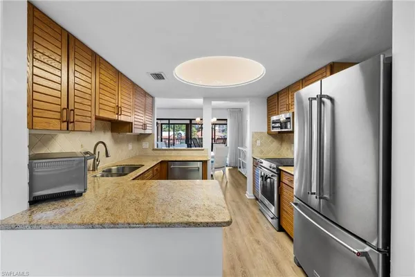 a kitchen with stainless steel appliances granite countertop a sink refrigerator and cabinets