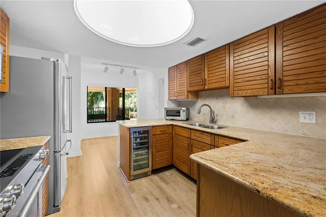 a kitchen with stainless steel appliances granite countertop a sink and wooden cabinets