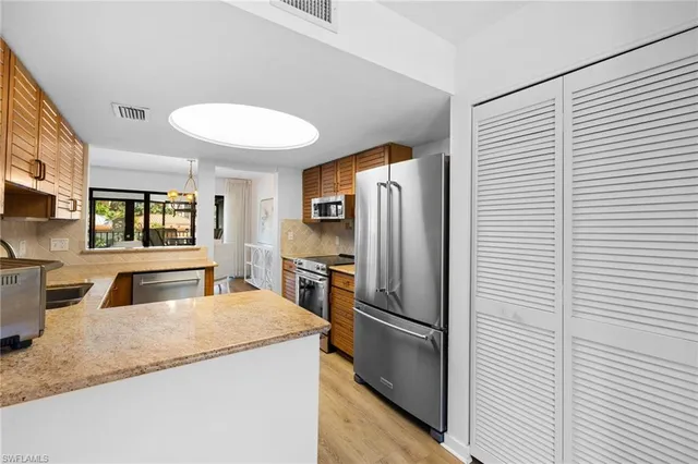 a kitchen with stainless steel appliances granite countertop a refrigerator a stove and a sink